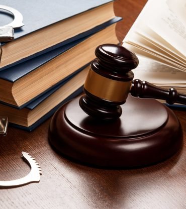 Gavel, books and handcuffs on wooden table